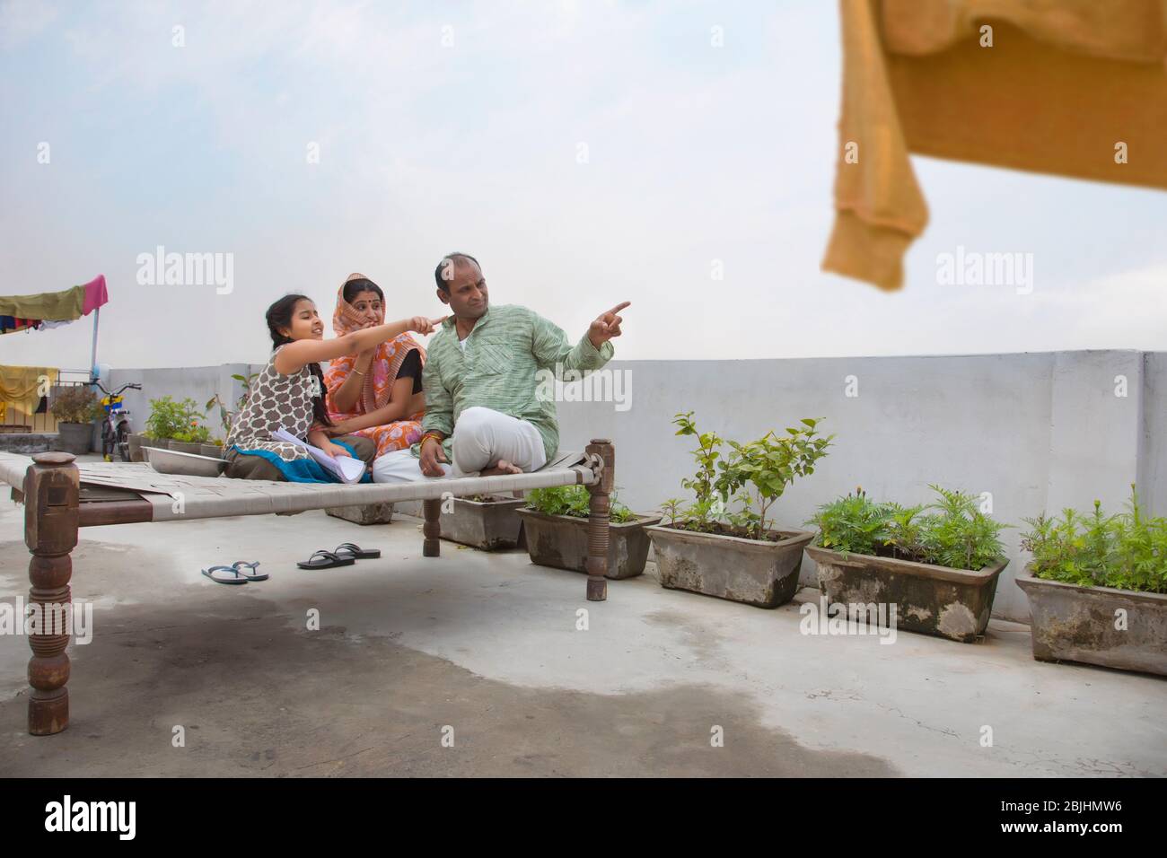 Indische Eltern sitzen zusammen auf einem Lagerbett und zeigen etwas Stockfoto