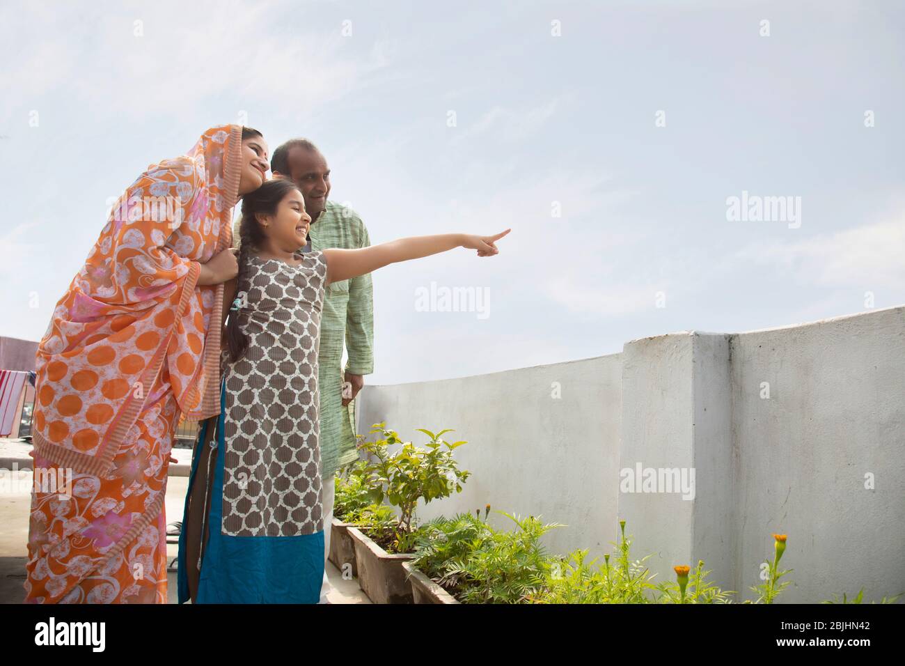 Indische Eltern und Tochter stehen auf dem Dach zusammen zeigen etwas Stockfoto