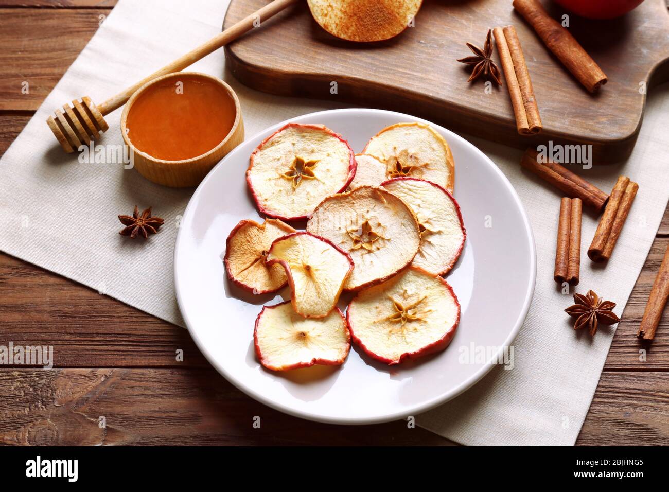 Komposition mit leckeren Apfelchips und Zimt auf Holztisch Stockfoto