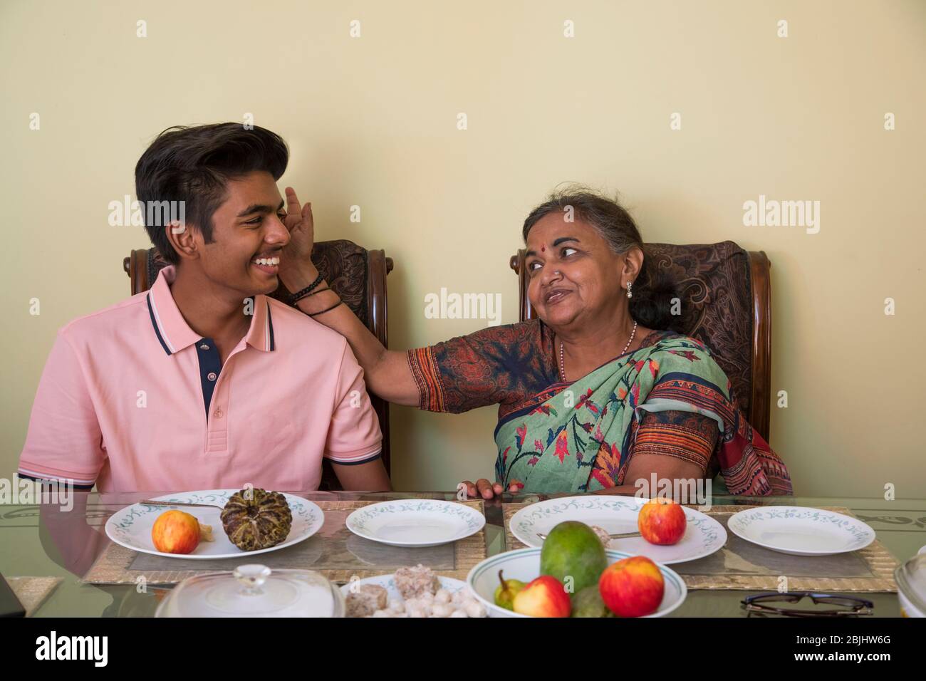 Großmutter segnet ihren Enkel auf dem Esstisch zu Hause. Stockfoto