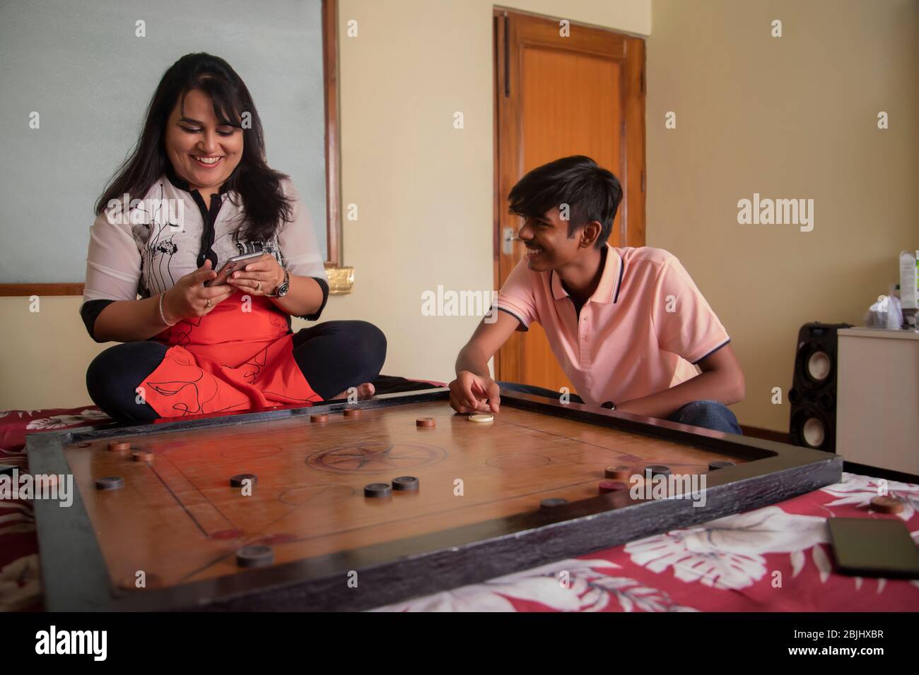 Sohn spielt mit seiner Mutter zu Hause Carrom-Board. Stockfoto