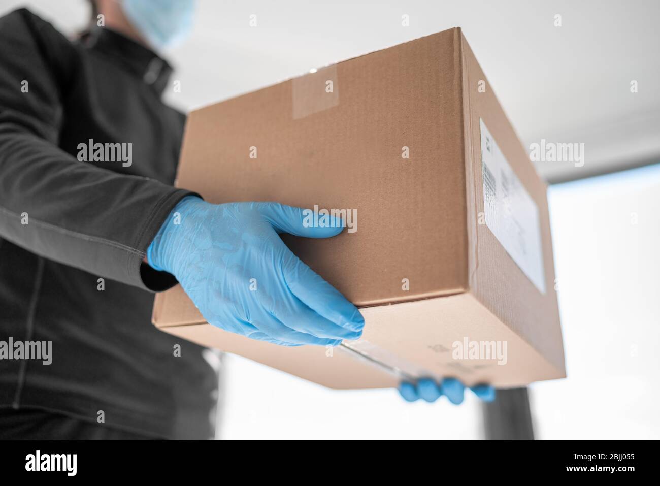 Home Delivery Shopping box Mann trägt Handschuhe und Schutzmaske Pakete an Tür liefern. Stockfoto