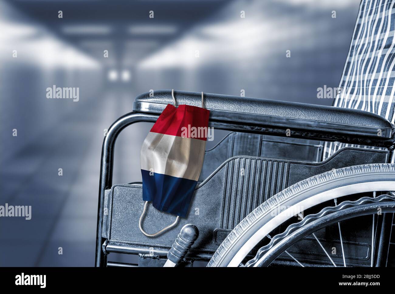 Flagge von Frankreich auf Gesichtsmaske hängen auf leeren Rollstuhl im Flur des französischen Krankenhauses oder Altersheim mit Kopie Raum. Konzept der Heilung Stockfoto