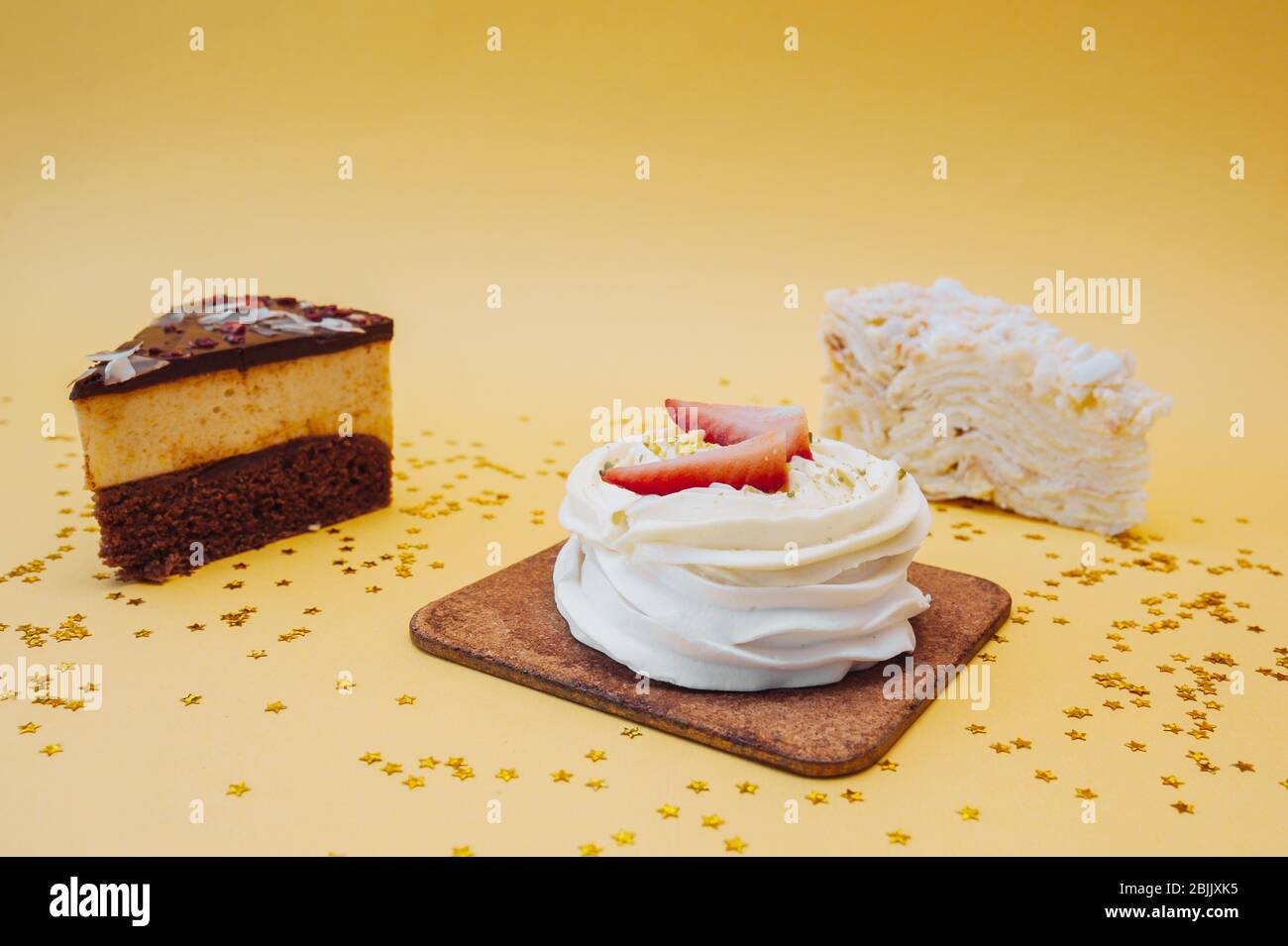 Drei verschiedene Arten von Süßigkeiten Kuchen auf einem gelben Hintergrund mit goldenen Pailletten Stockfoto