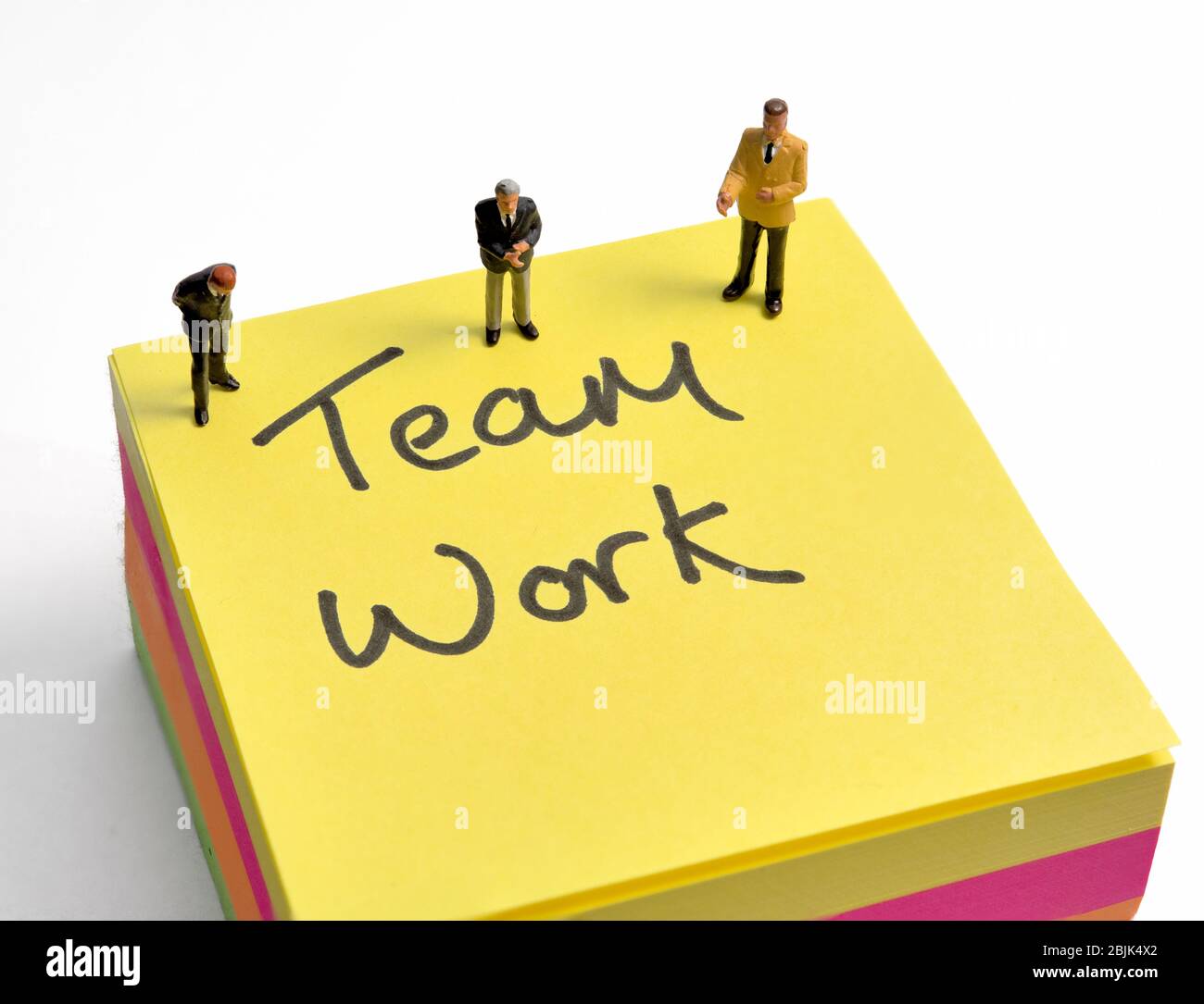 Teamarbeit, Post it Note, Miniaturfiguren auf weißem Hintergrund Stockfoto