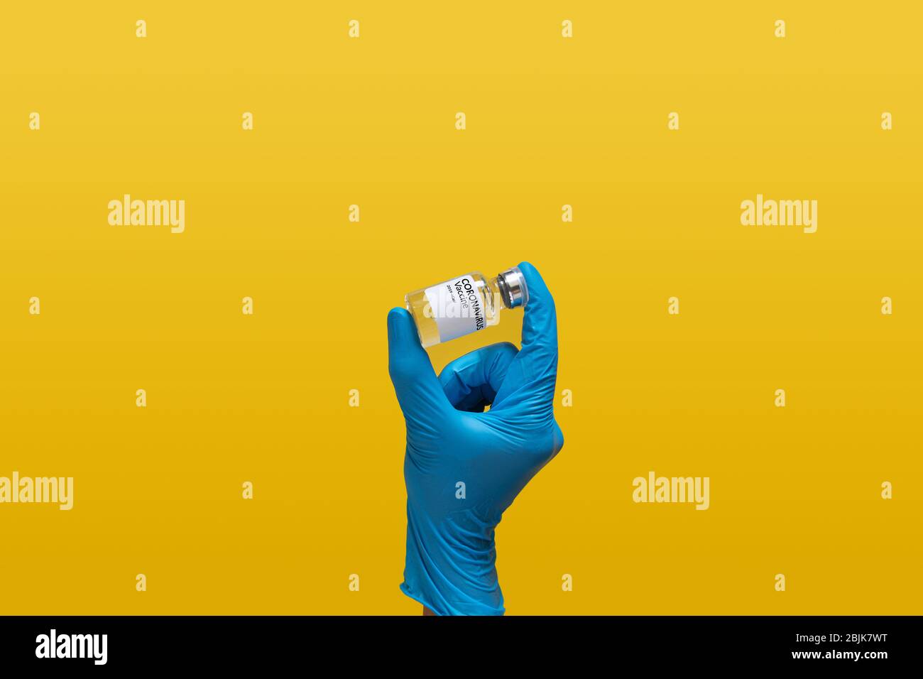Arzt im Labor tragen blauen Gummihandschuh mit Coronavirus Impfstoff Dosis Flasche Etikett, isoliert auf gelbem Hintergrund. Labor analysieren Stockfoto