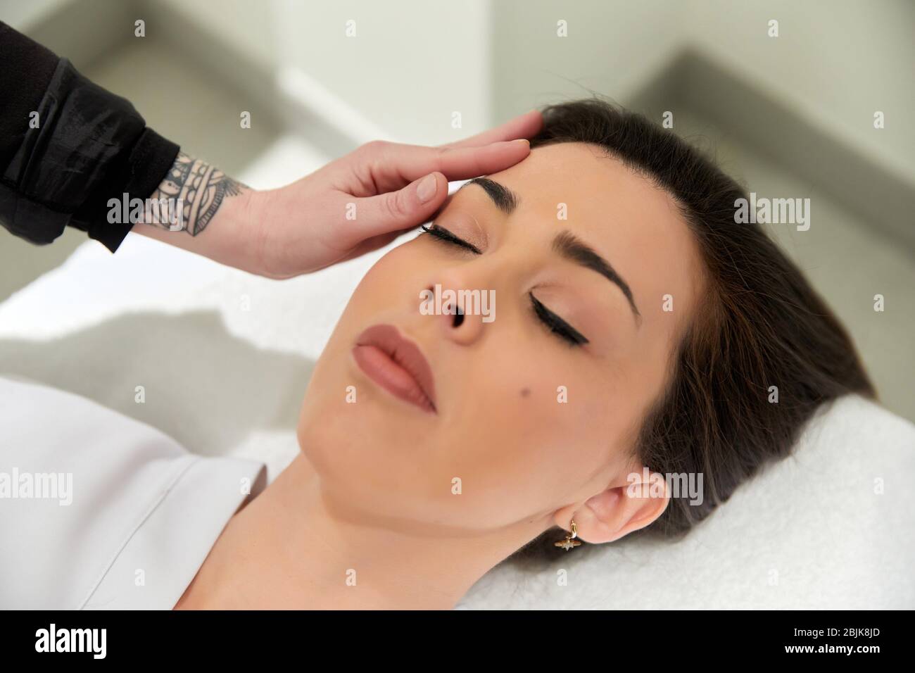 Make-up-Künstler, der Behandlungen an den Augenbrauen einer Frau, Friseursalon und Schönheitsklinik durchführt. Stockfoto