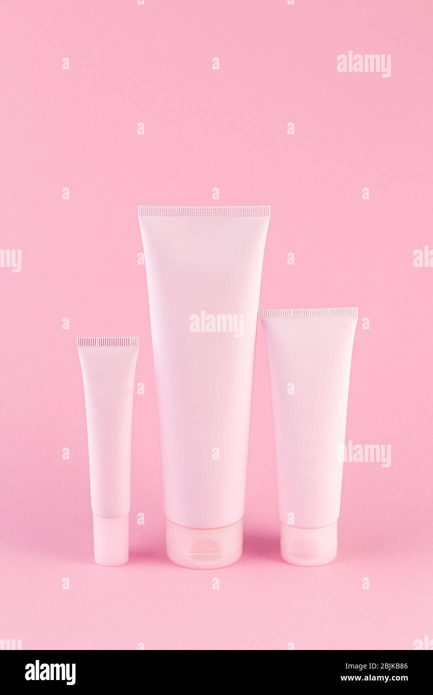 Sammlung von drei kosmetischen Röhren auf pastellrosa Hintergrund. Plastikröhre mit Gesicht oder Körper Creme auf rosa mit Kopierraum. Kunststoffröhre für Medizin Stockfoto