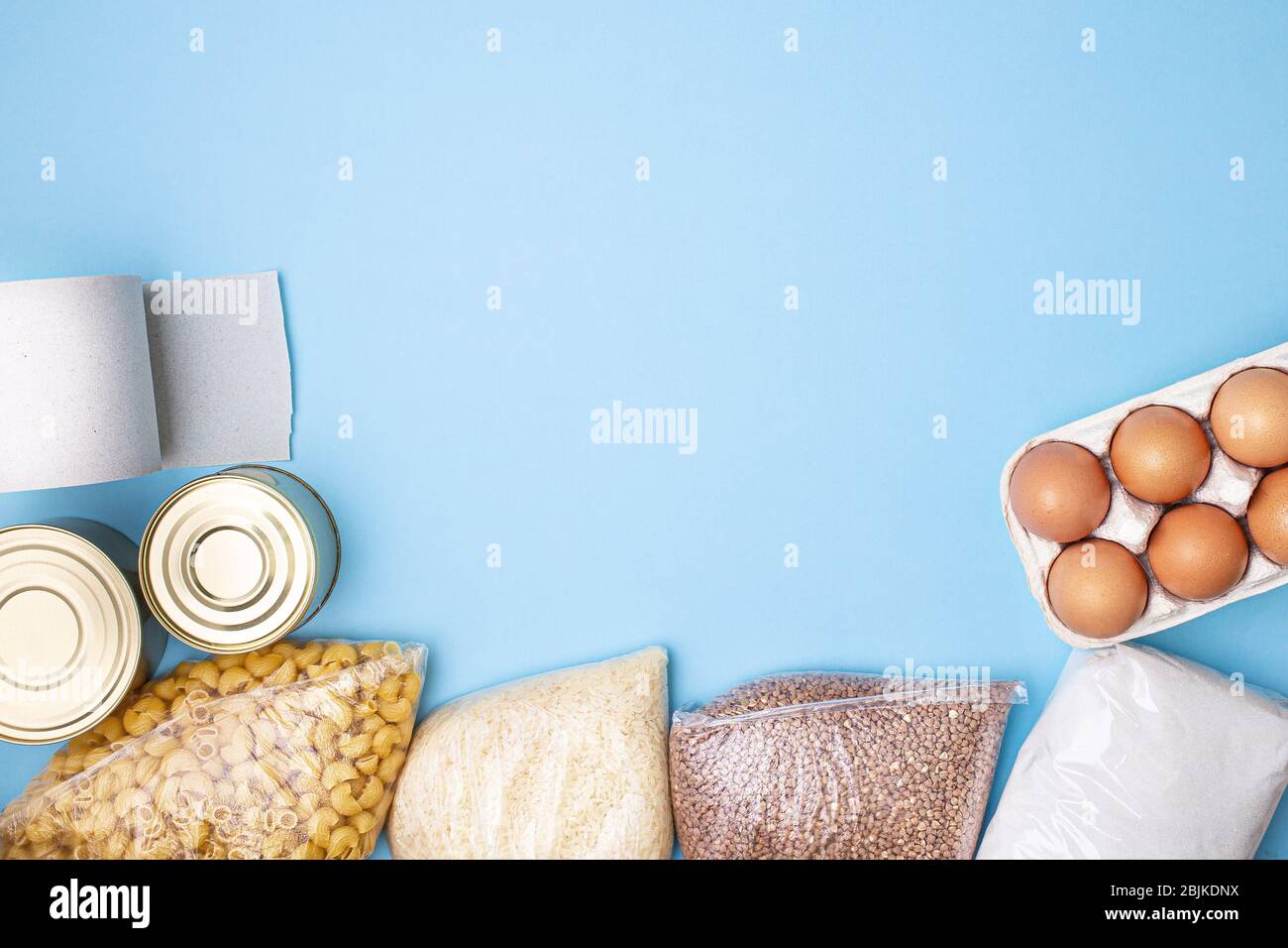 Lieferkost. Reis, Buchweizen, Nudeln, Dosenfutter, Zucker, Toilettenpapier auf blauem Hintergrund. Sammeln Sie freiwillig Lebensmittel. Spende, Coronavirus Quarantin Stockfoto