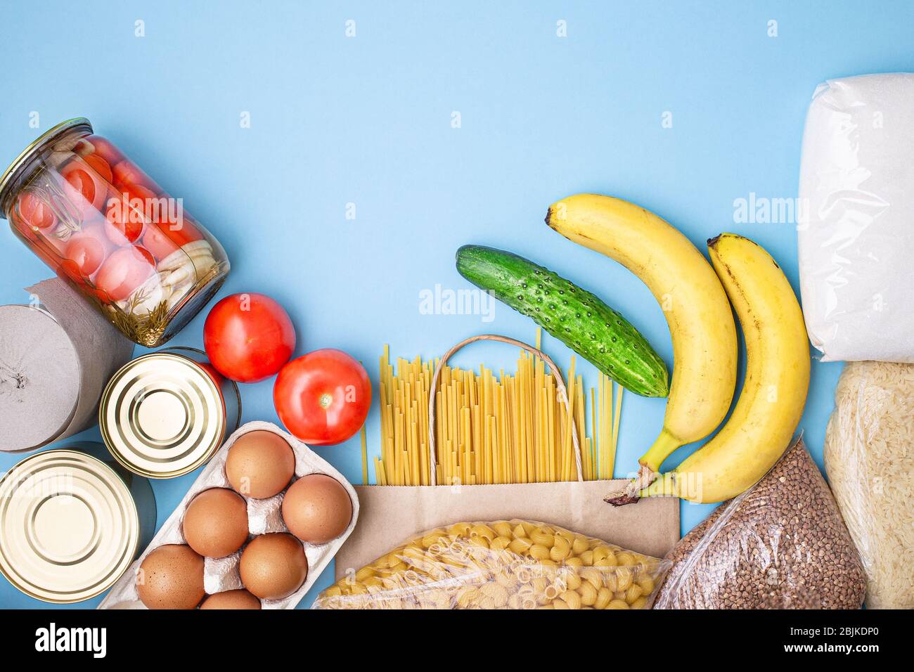 Lieferkost. Reis, Buchweizen, Nudeln, Dosenfutter, Zucker, Tomaten, Gurken, Bananen auf blauem Hintergrund. Sammeln Sie freiwillig Lebensmittel. Spende, coron Stockfoto