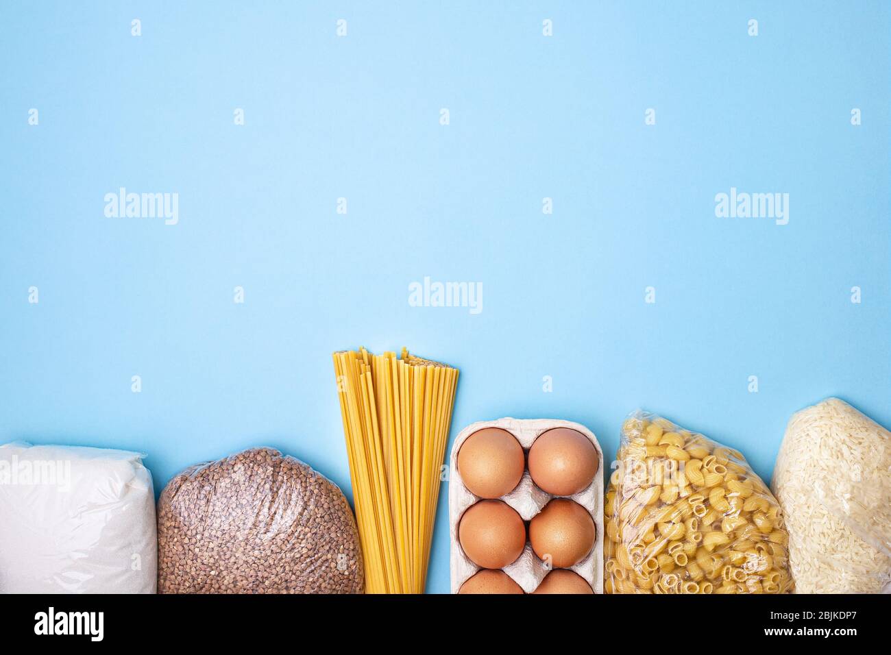 Lieferkost. Reis, Buchweizen, Nudeln, Dosenfutter, Zucker auf blauem Hintergrund. Sammeln Sie freiwillig Lebensmittel. Spende, Quarantäne des Coronavirus. Speisenangebot Stockfoto