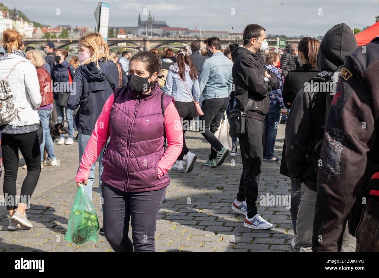 PRAG, TSCHECHISCHE REPUBLIK - 25. APRIL 2020: Menschen einkaufen auf dem wiedereröffneten Naplavka Bauernmarkt, tragen Schutzmaske wegen der Korona Stockfoto