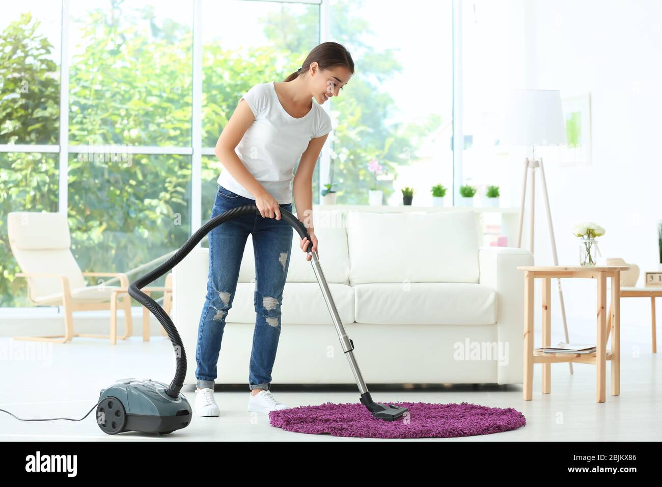 Frau putzt kleinen Teppich mit Staubsauger im Wohnzimmer Stockfotografie -  Alamy