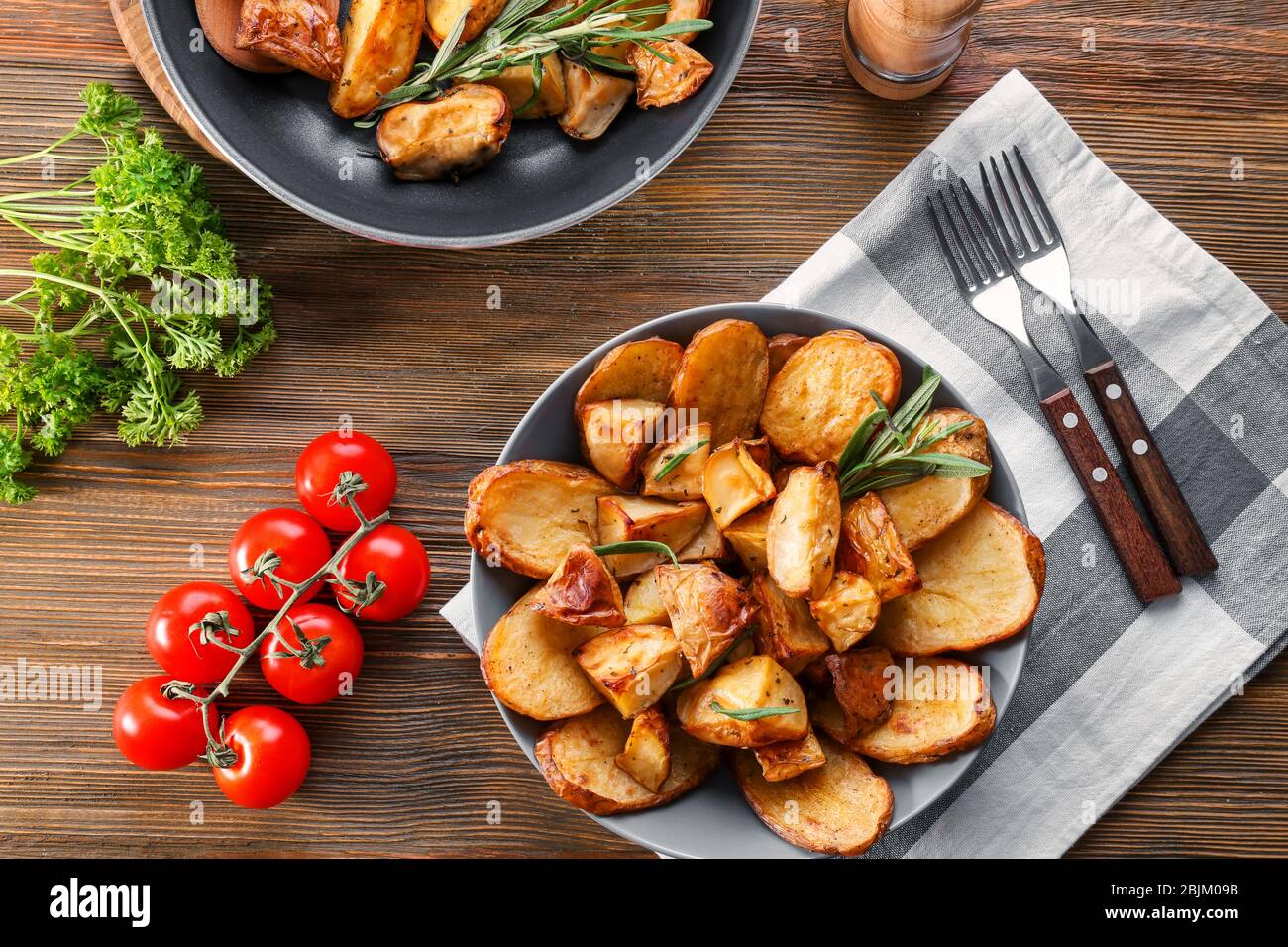 Zusammensetzung mit Teller mit gebackenen Rosmarinkartoffeln auf dem Tisch Stockfoto