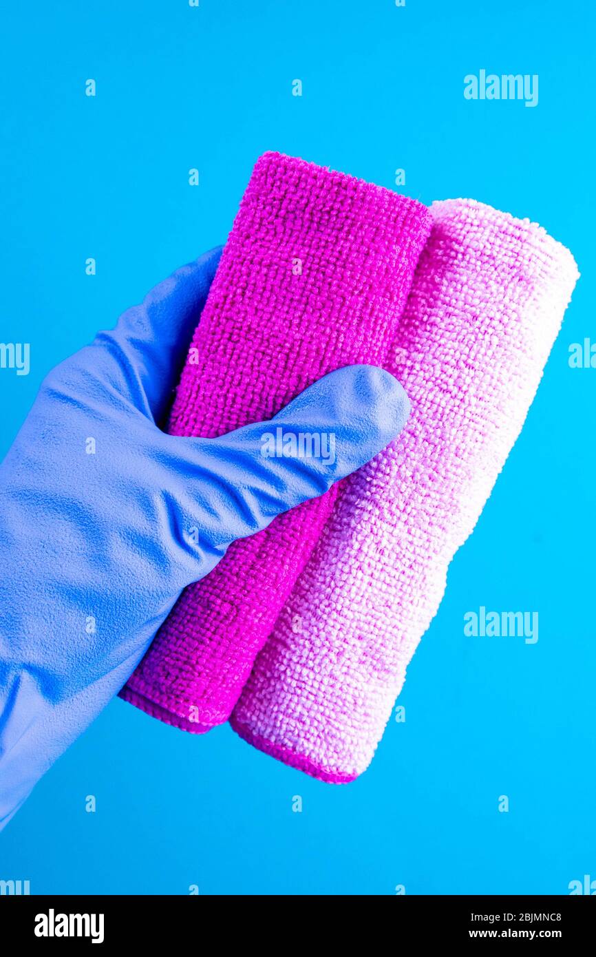 Weibliche Hand in blauem Gummi gHands in Gummi-Schutzhandschuhe halten Lappen. Waschmittel für verschiedene Oberflächen in Küche, Bad und anderen Räumen Stockfoto