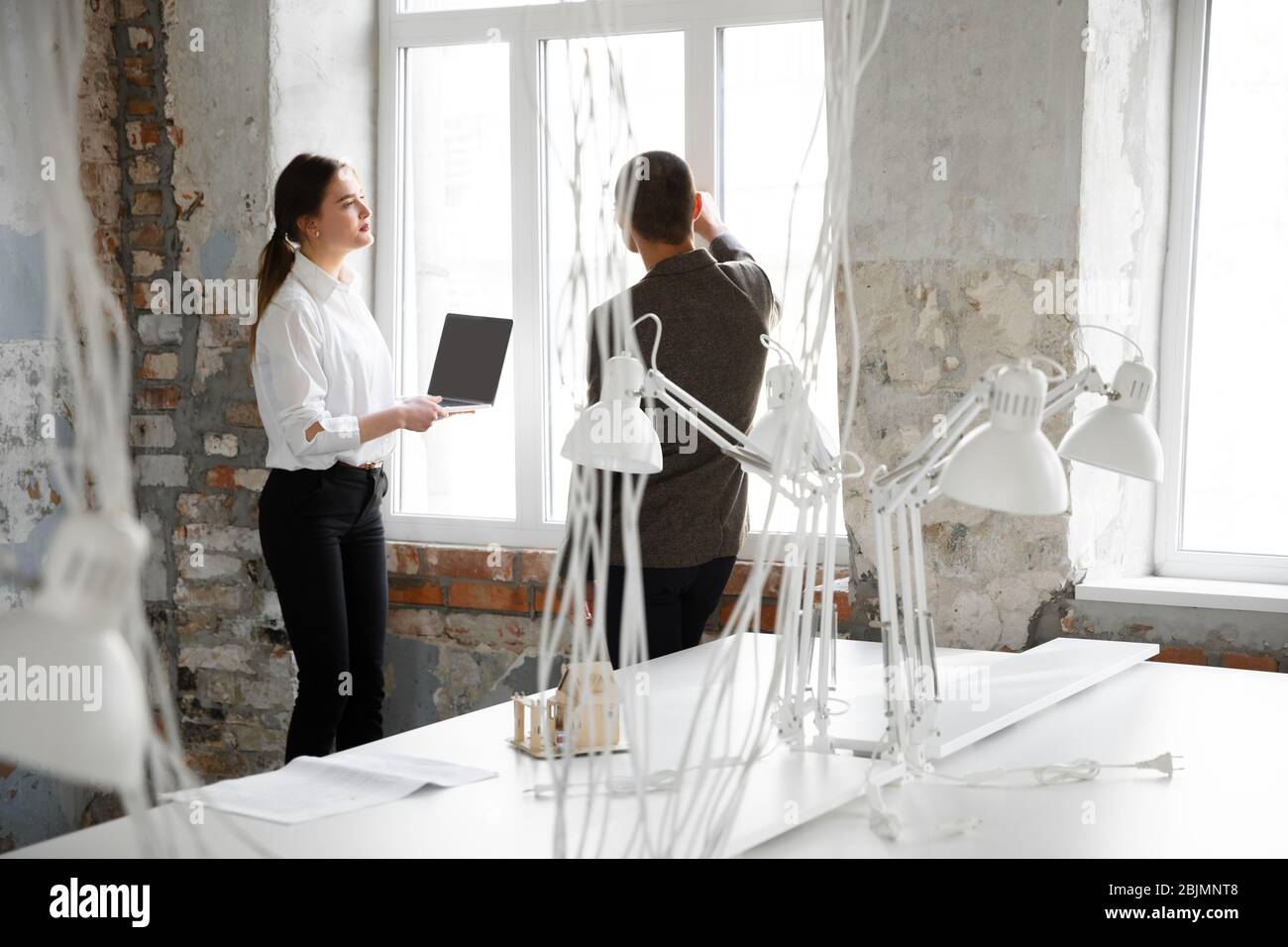 Details. Weibliche Maklerin zeigt einem jungen Mann nach einer Diskussion über die Baupläne ein neues Zuhause. Die Wahl der Baustoffe, Reparatur, Technologien in Smart House. Umzug, neues Home-Konzept. Stockfoto