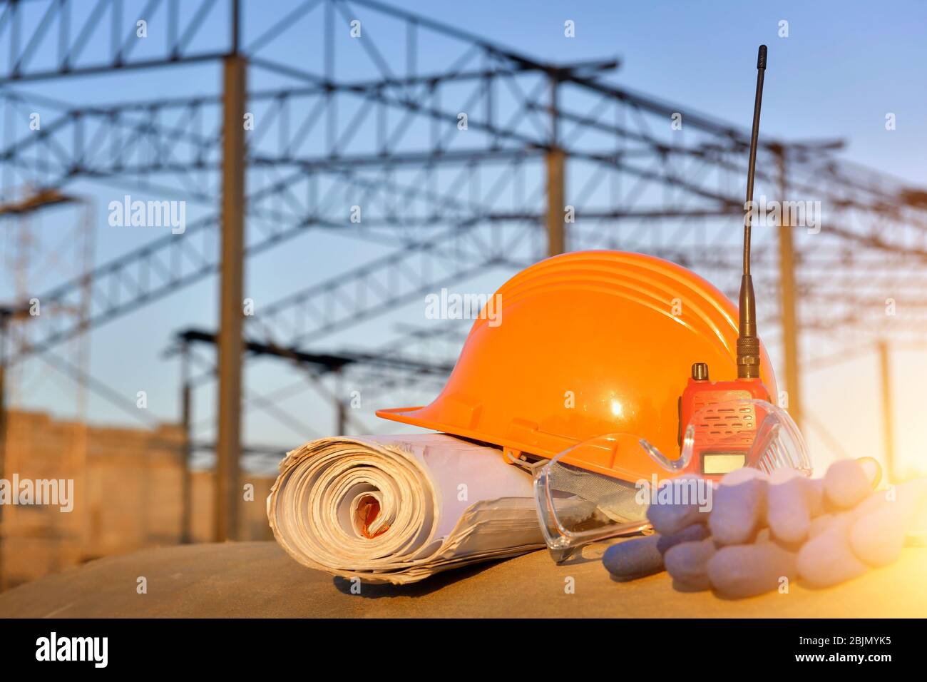 Schutzhelm, Walkie Talkie, Blaupause und Handschuhe auf einer Baustelle Stockfoto