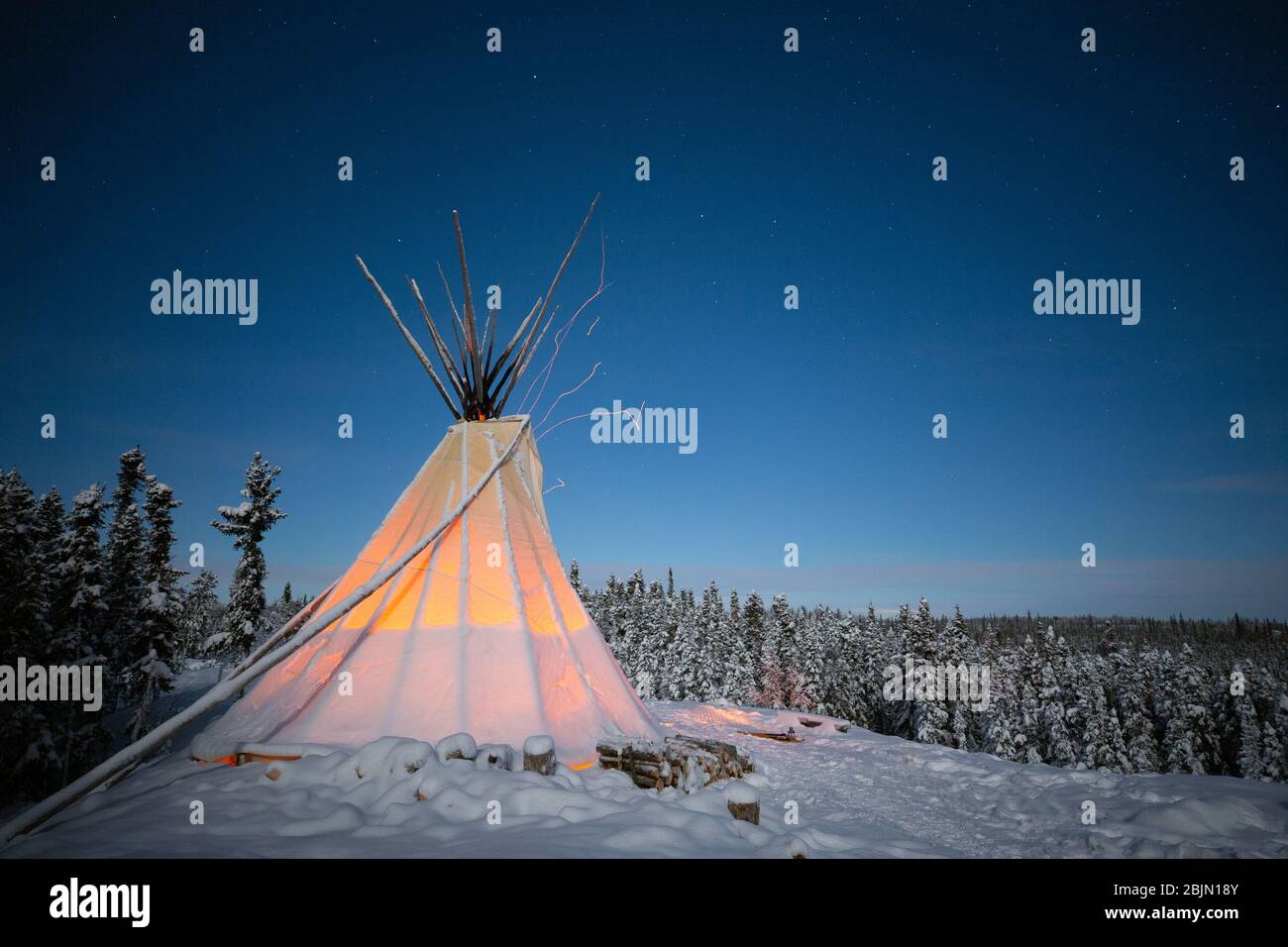 Glühendes Tipi im Winterwald bei Nacht, Yellowknife, Northwest Territories, Kanada Stockfoto