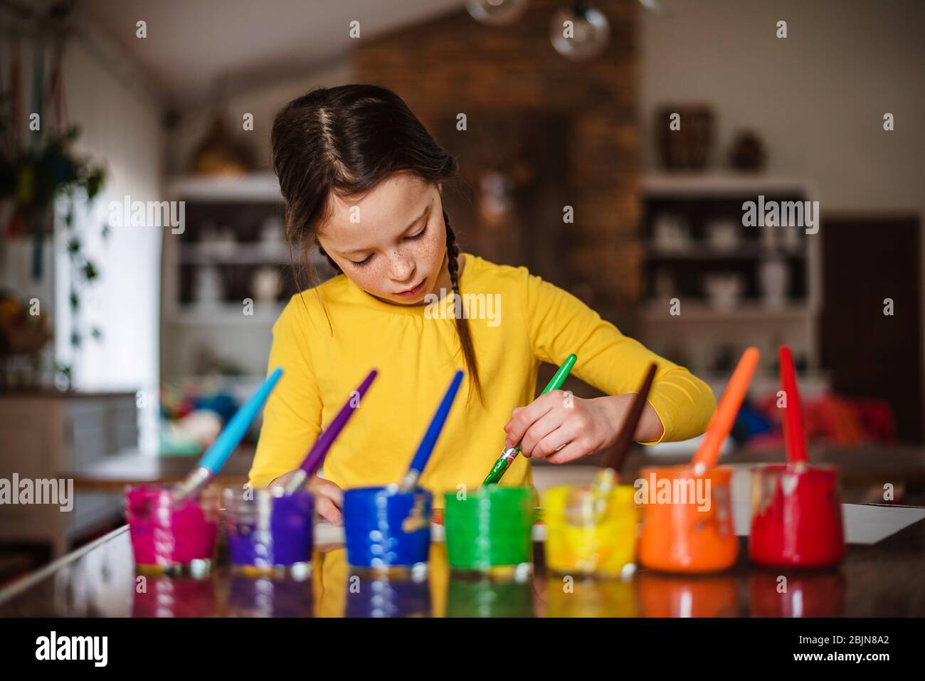 Mädchen sitzt in der Küche Malerei einen Regenbogen Stockfoto