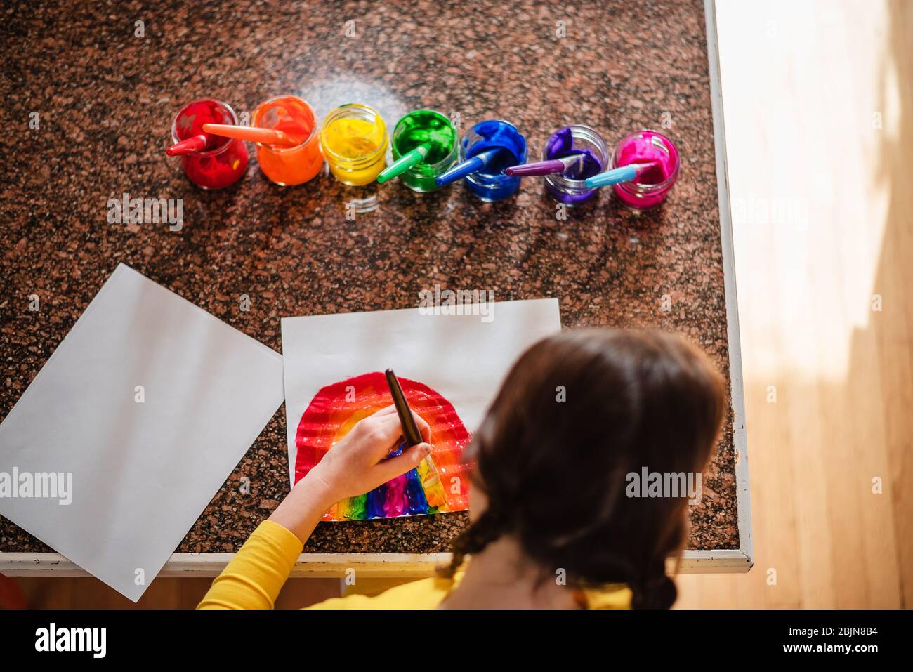 Mädchen sitzt in der Küche Malerei einen Regenbogen Stockfoto