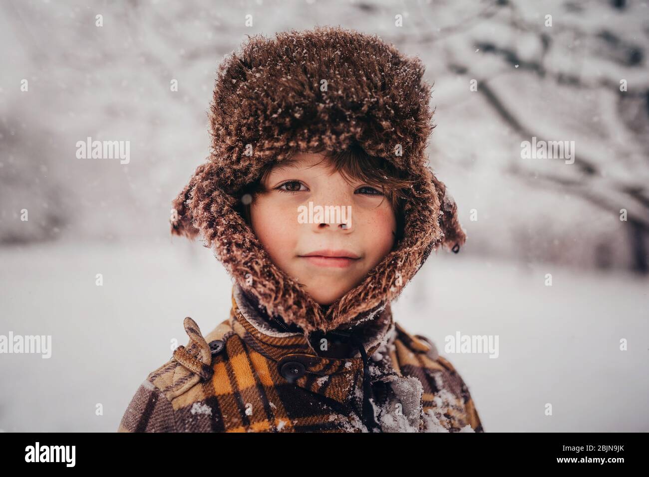 Porträt eines Jungen mit Jägermütze im Schnee, USA Stockfoto