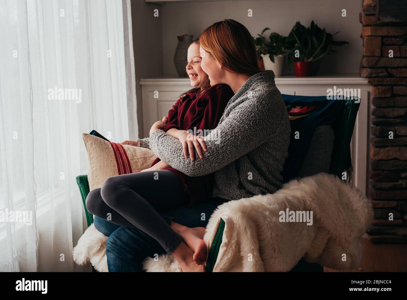 Mutter und Tochter kuscheln in einem Sessel Stockfoto