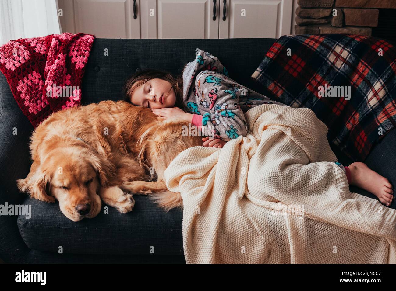 Mädchen schläft auf einem Sofa mit ihrem Hund Stockfoto