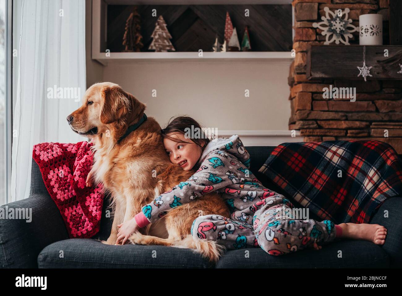 Mädchen sitzt auf einem Sofa mit ihrem Hund Stockfoto
