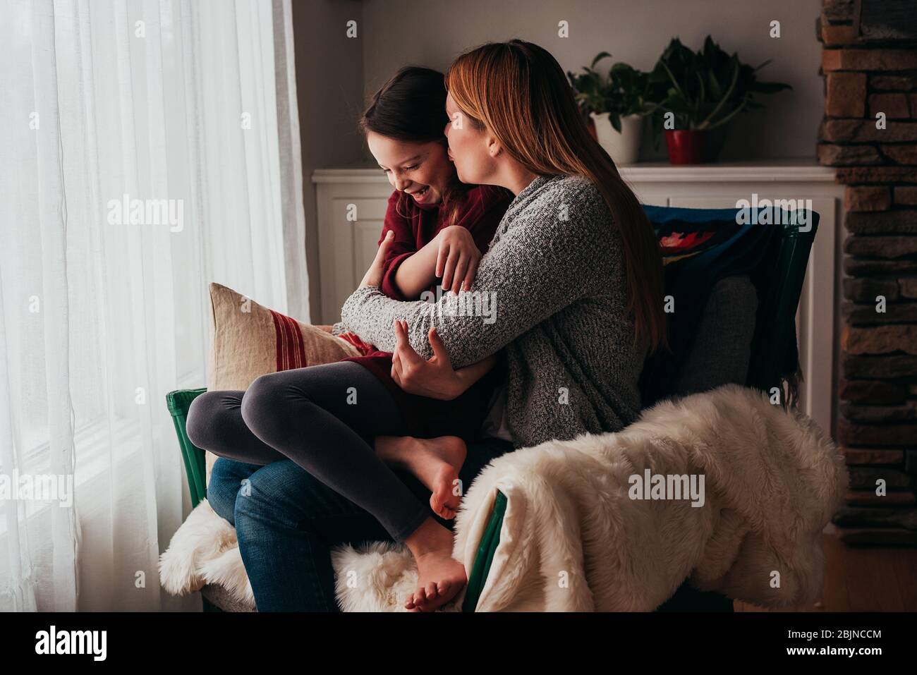 Mutter und Tochter kuscheln in einem Sessel Stockfoto