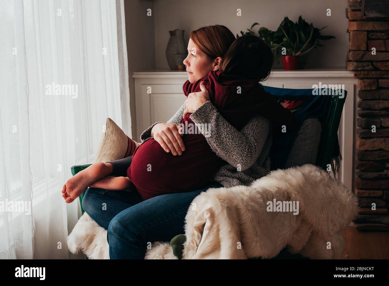Mädchen sitzt auf dem Schoß ihrer Mutter kuscheln Stockfoto