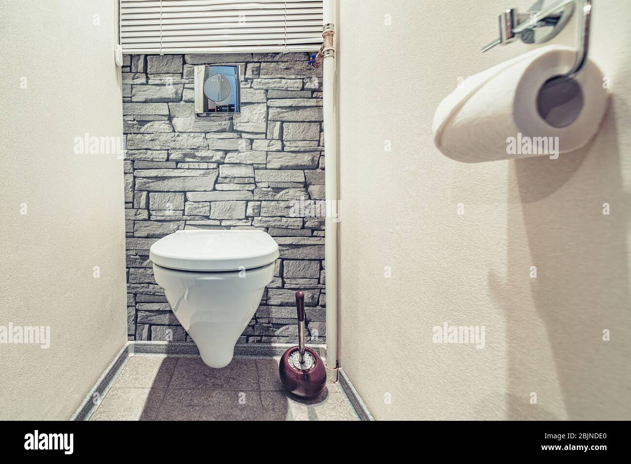 Weiß eingebaute WC-Schüssel in modernem Bad mit Papierhalter und WC-Bürste Stockfoto