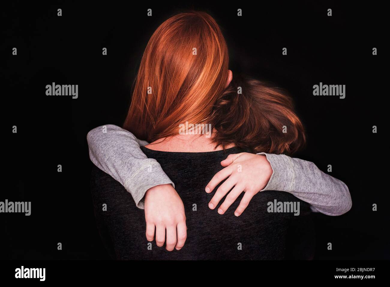 Rückansicht einer Frau, die ihren Sohn umarmt Stockfoto