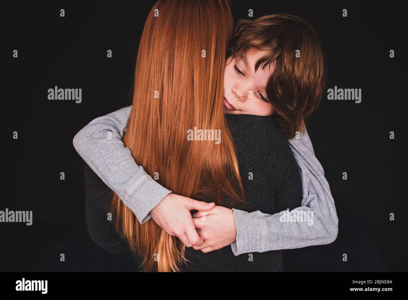 Rückansicht einer Frau, die ihren Sohn umarmt Stockfoto