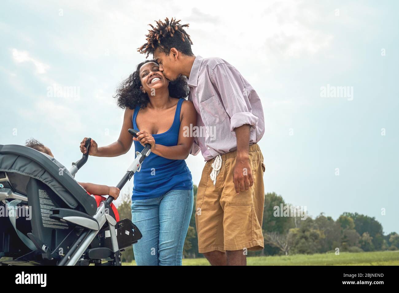 Glückliche afrikanische Familie, die Spaß zusammen im öffentlichen Park hat - Afro Mutter und Vater mit ihrer Tochter, die Zeit zusammen am Wochenende draußen genießen Stockfoto