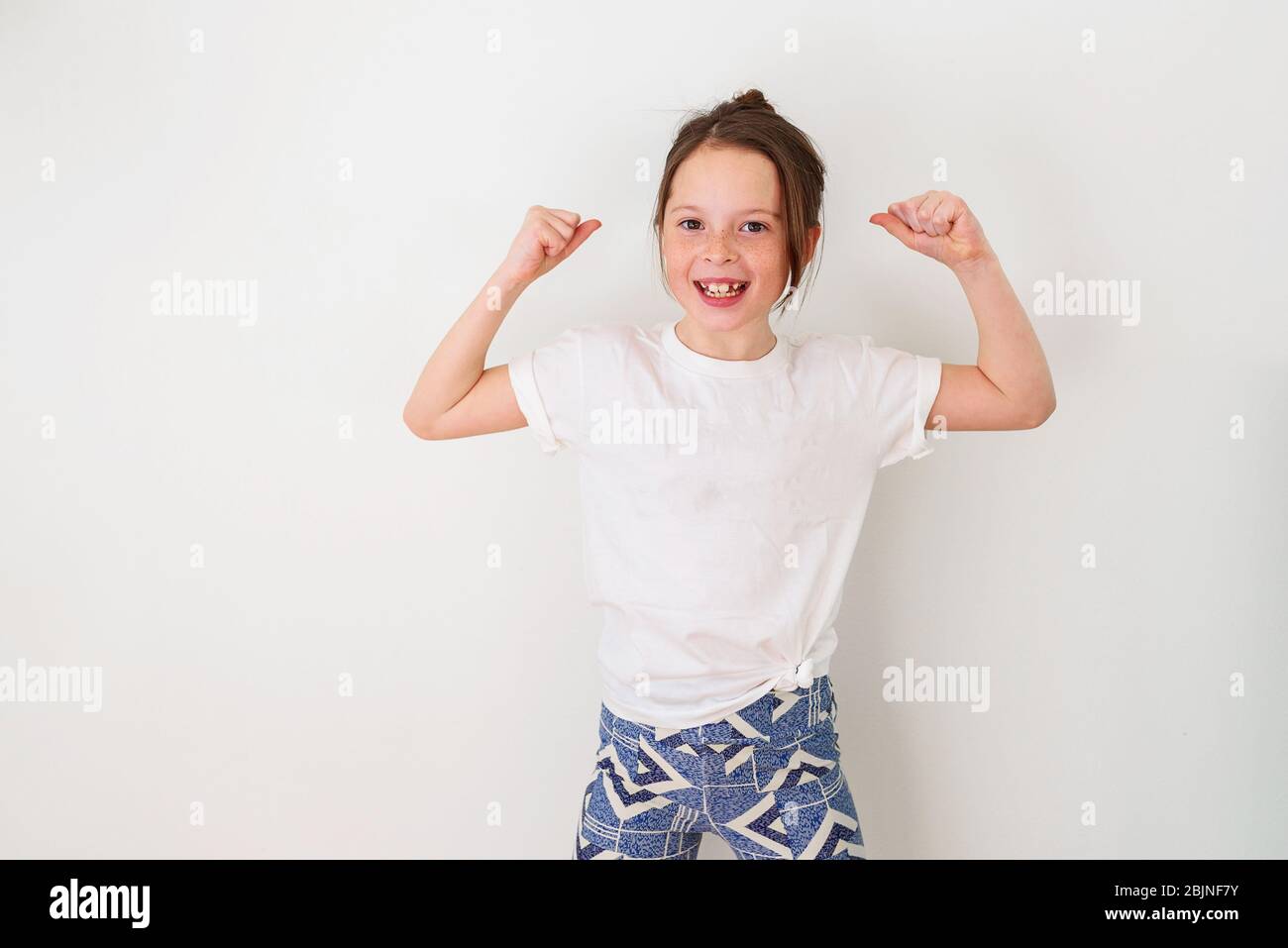 Mädchen, das an einer Wand steht und ihre Muskeln biege Stockfoto