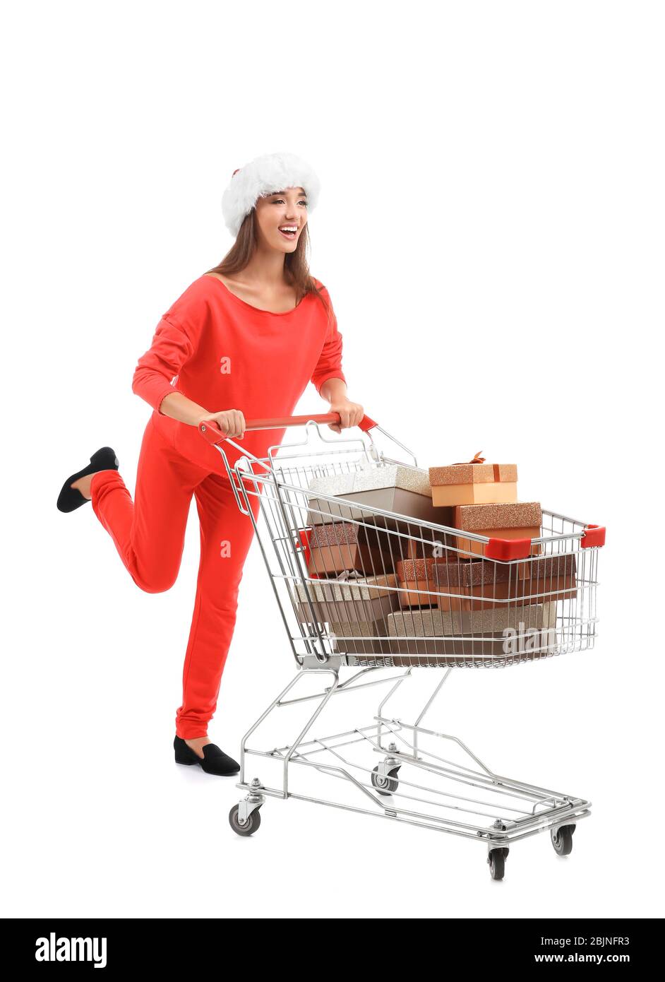 Junge Frau in Santa Hut mit Geschenken im Warenkorb auf weißem Hintergrund. Konzept des Boxtages Stockfoto