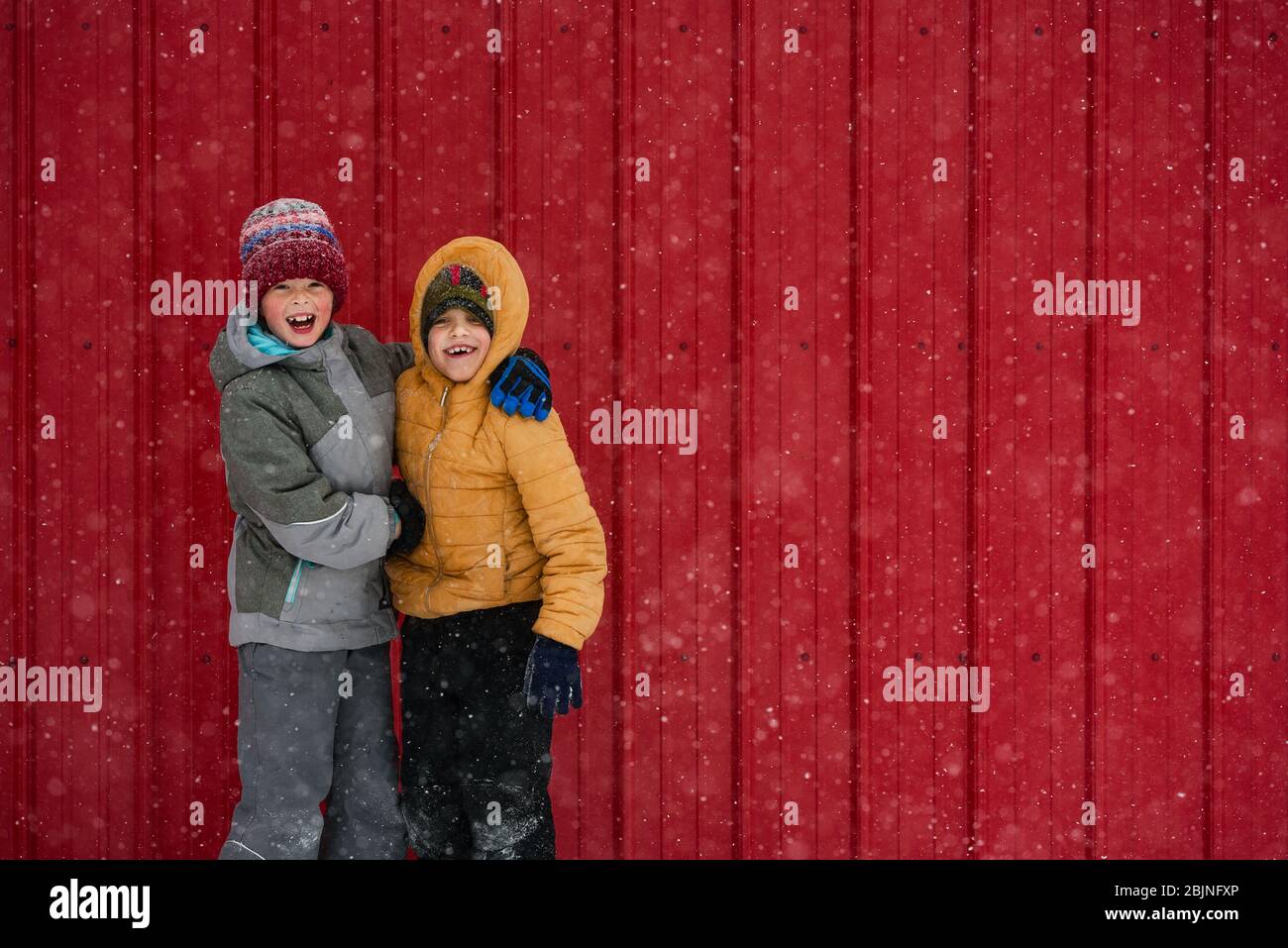 Zwei glückliche Kinder, die vor einem roten Haus herumwirren, USA Stockfoto