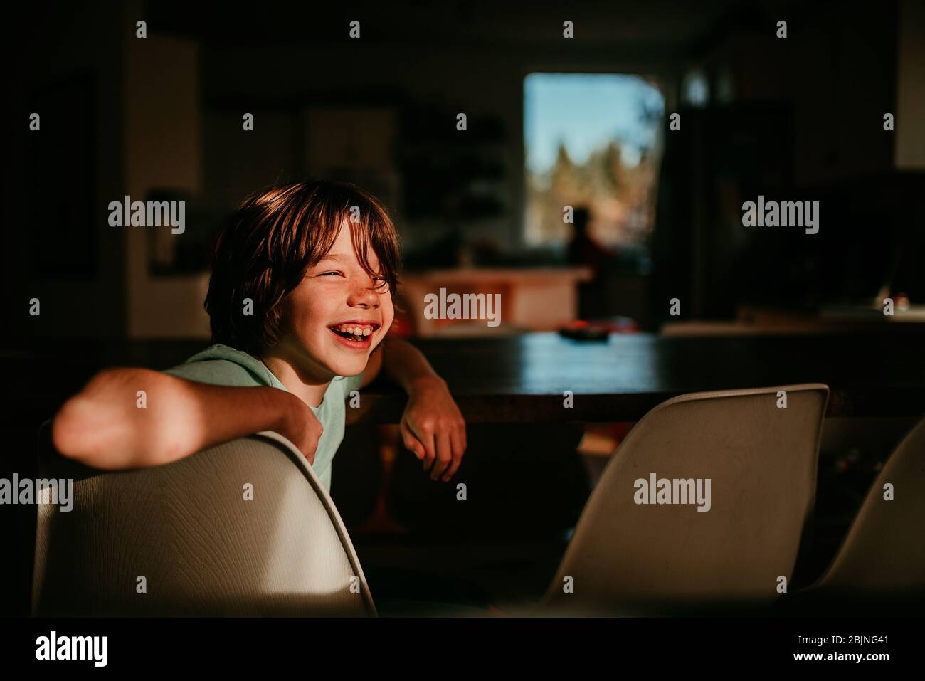 Happy Boy sitzt an einem Esstisch Stockfoto