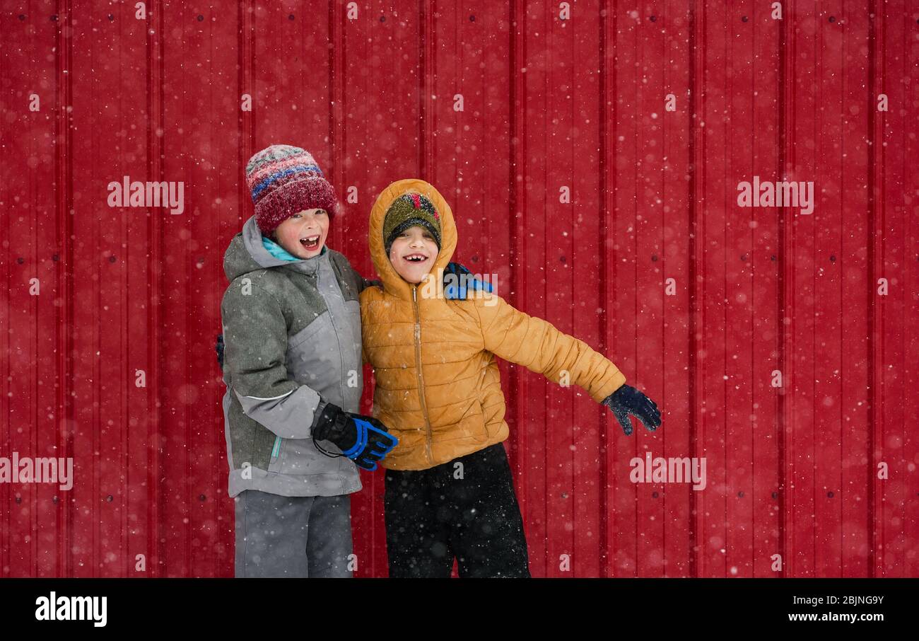 Zwei glückliche Kinder, die vor einem roten Haus herumwirren, USA Stockfoto