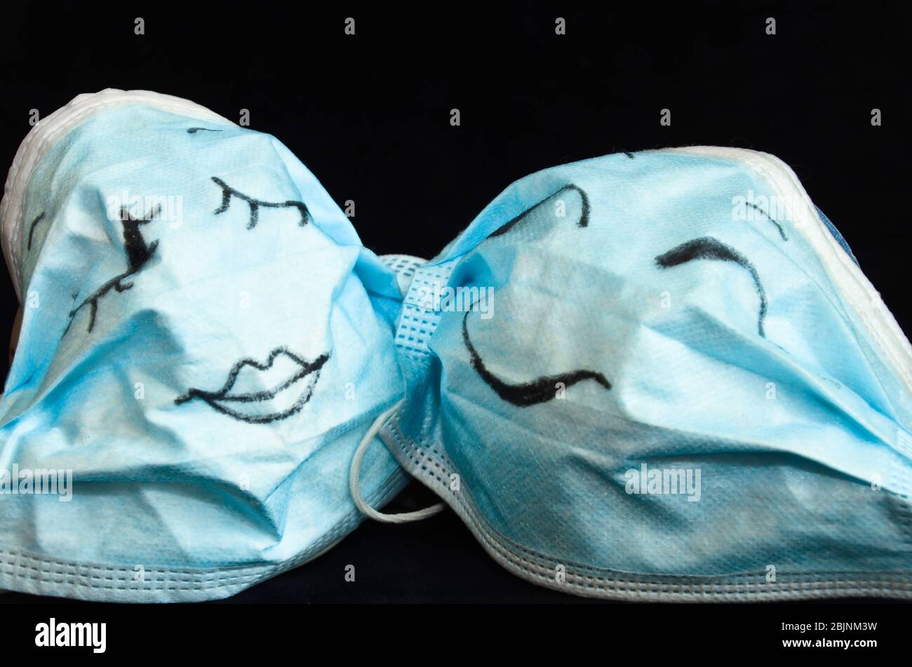 Zwei lustige Schutzmasken gegen Corona, mit Gesichtern, wie ein Mann und  eine Frau, flirten vor einem schwarzen Hintergrund zusammen Stockfotografie  - Alamy