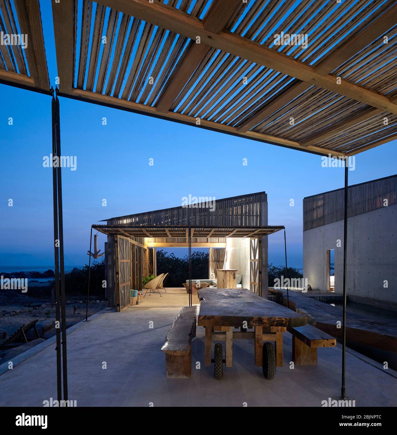 Blick in die Dämmerung mit Blick auf die Gemeinschaftseinheit und den Essbereich. Casa Naila, Puerto Escondido, Mexiko. Architekt: BAAQ, 2020. Stockfoto
