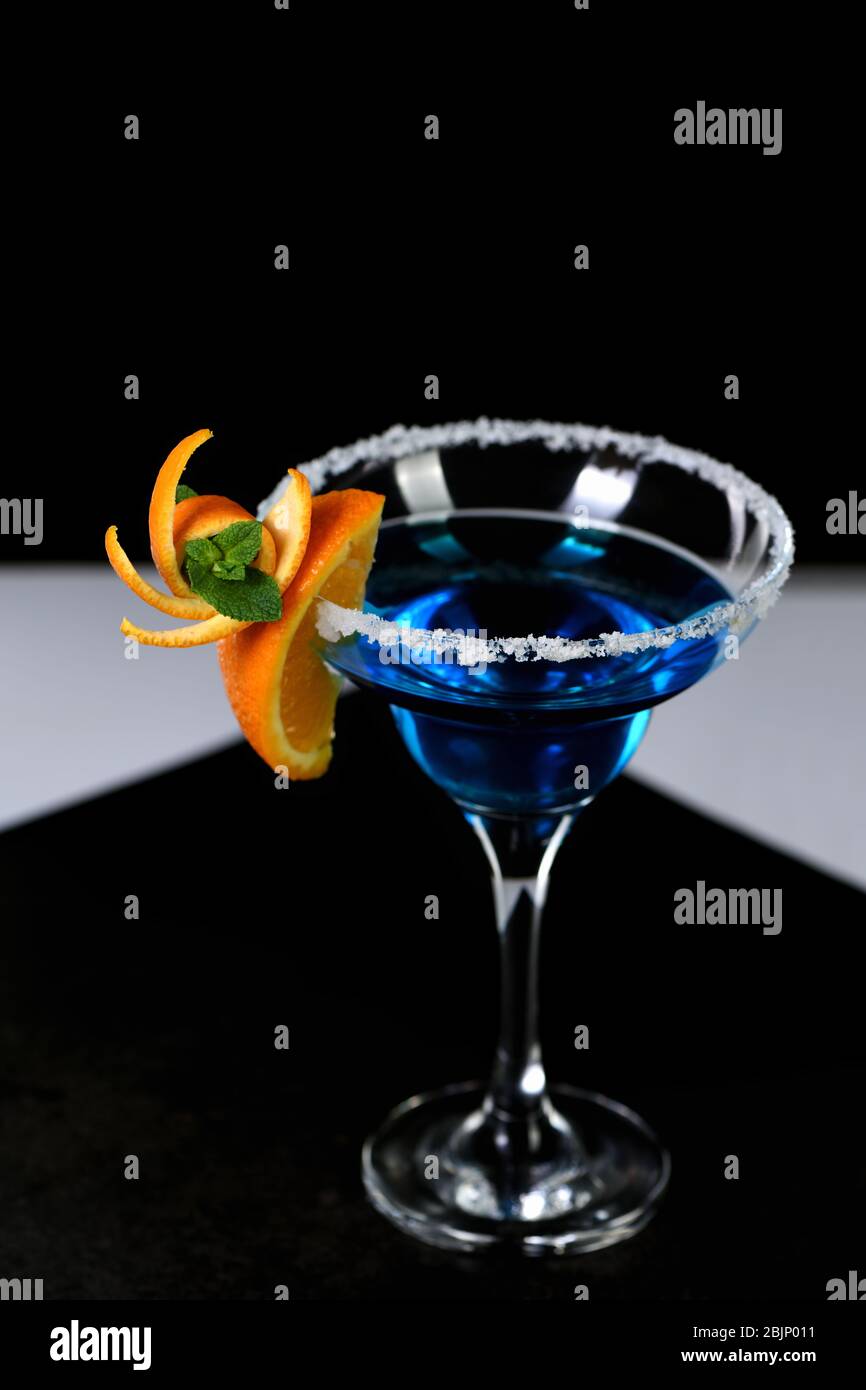 Dekoration für einen Cocktail aus Orange und Minze. Elegante und originelle Präsentation. Martini Blue Curacao auf schwarzem Hintergrund Stockfoto