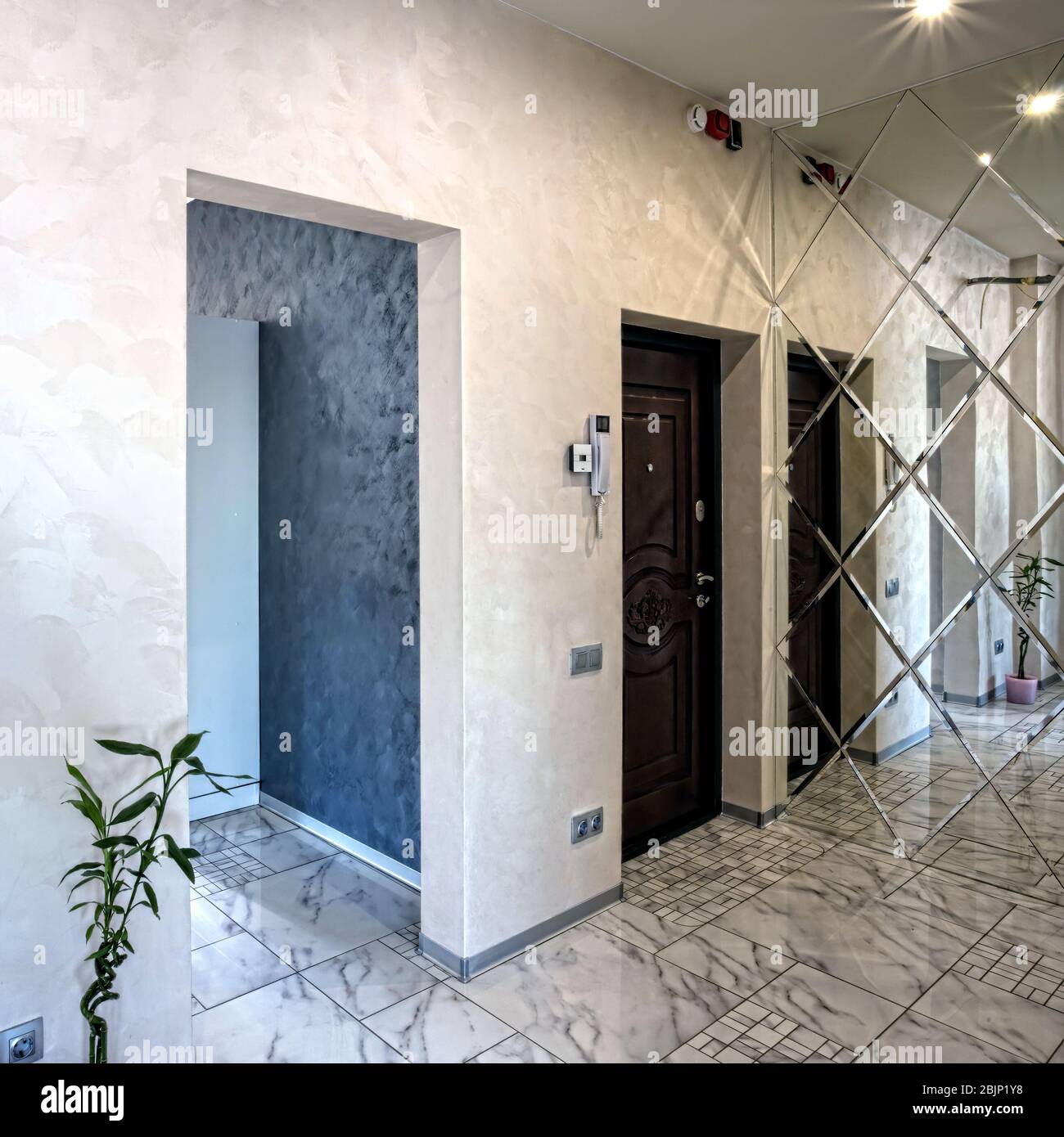 Blick auf das Foyer im Inneren. Helles Interieur einer schönen modernen Halle im Stil des Minimalismus mit weißen Wänden, einem schönen Kronleuchter, einem großen mir Stockfoto