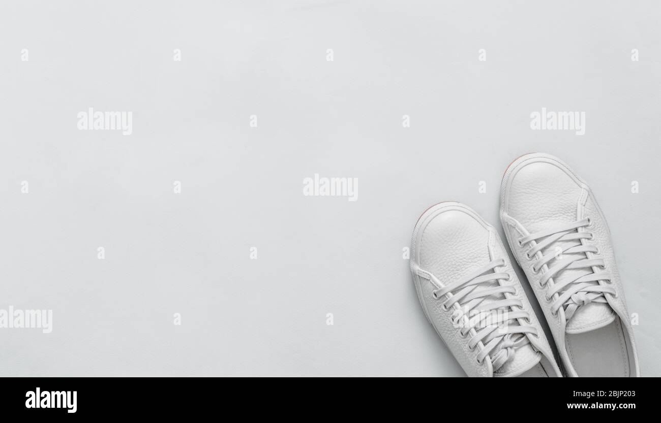 Sneaker aus weißem Leder auf blauem Hintergrund. Ein Paar trendy weiße Sportschuhe oder Sneaker mit Copy-Raum für Text oder Design. Overhead-Aufnahme von neuen weißen Sneakers. Draufsicht oder flaches Lay. Banner Stockfoto