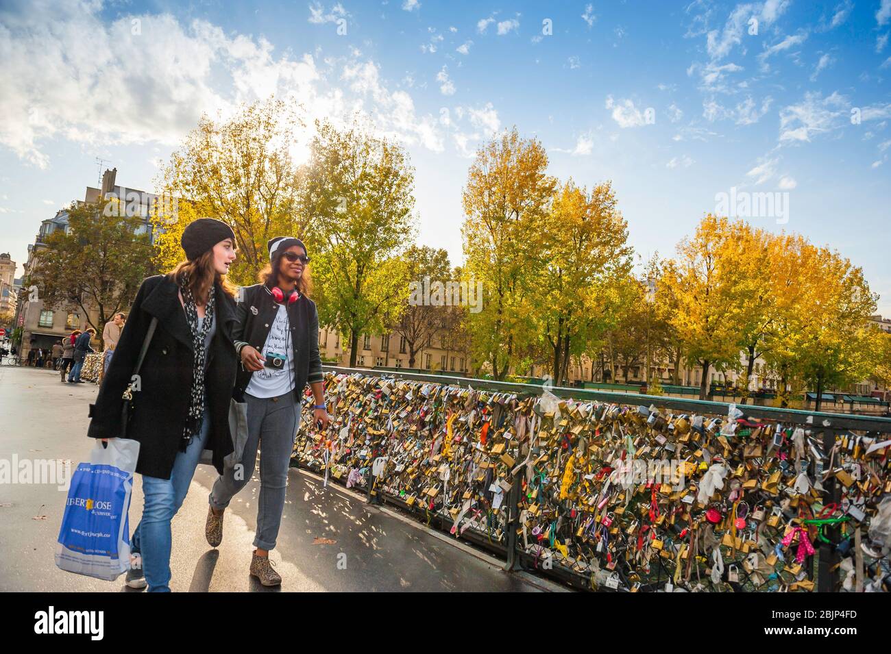 Freundinnen reisen nach Paris, mit Blick auf zwei junge Freundinnen, die an einem Herbsttag in Frankreich über die Pont de l'Archeveche im Zentrum von Paris gehen. Stockfoto