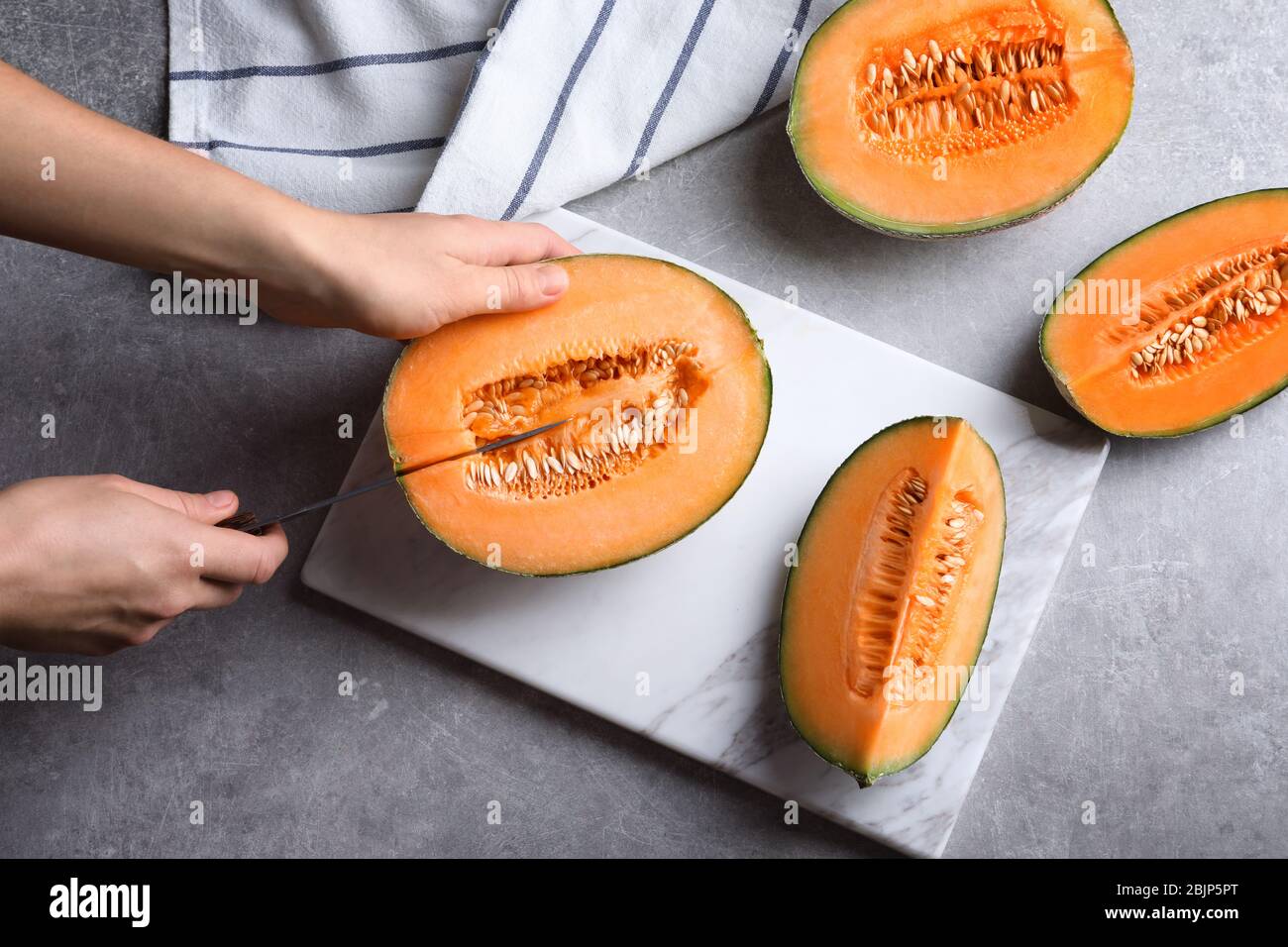 Frau schneidet Melone auf Küchentisch Stockfoto