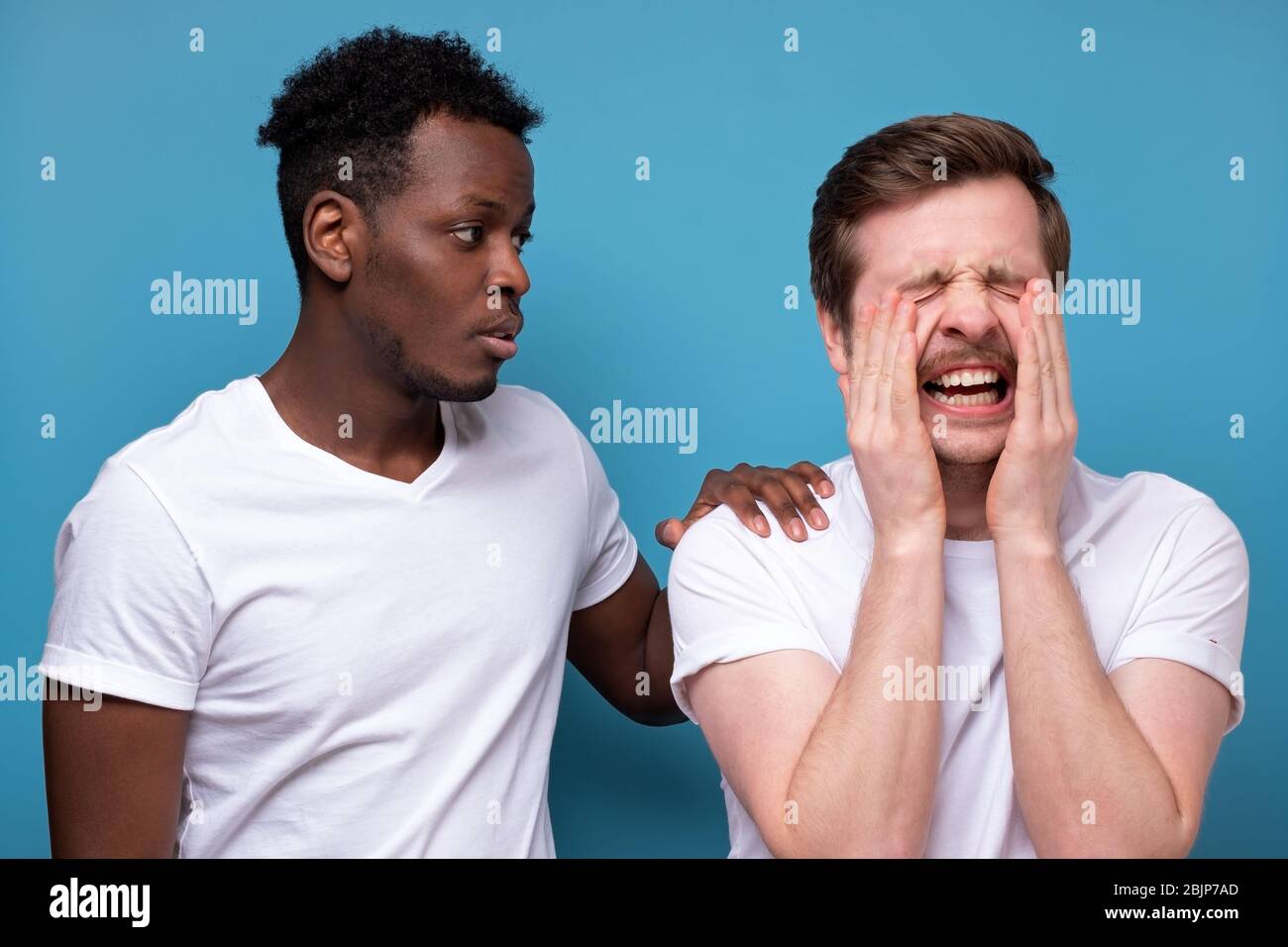 afroamerikanischer Mann beruhigt seinen Kollegen oder Freund, der Probleme hat, miserable Gesichtsausdrücke, die Hände auf seinen Schultern hält, steht eng Stockfoto