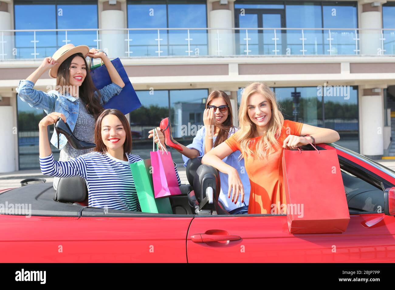 Schöne junge Frauen mit Einkaufstaschen im Cabrio im Freien Stockfoto