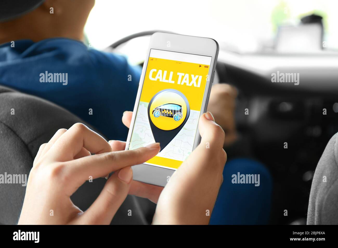 Junge Frau mit Handy im Taxi Stockfoto
