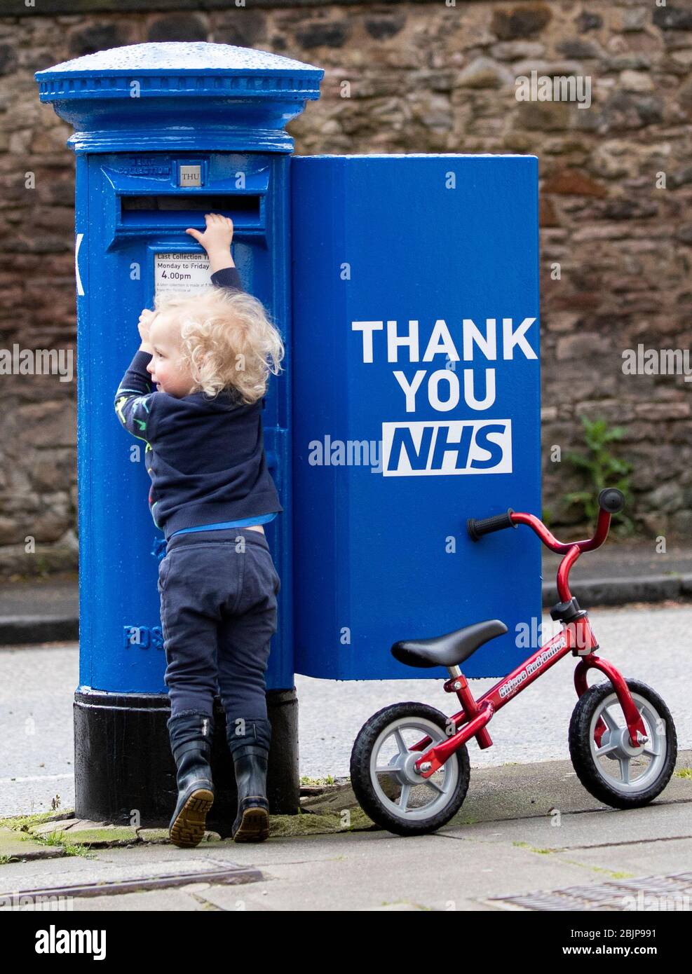 Xander Irvine, drei, inspiziert einen der speziell dekorierten Briefkästen in Edinburgh, die blau gestrichen wurden, um die NHS-Arbeiter und Pfhalter zu unterstützen, die gegen die Coronavirus-Pandemie kämpfen. Stockfoto